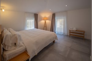 Zimmer „Materia“ in der Villa Patria mit Doppelbett, Holzmöbeln und Blick auf den Luganer See