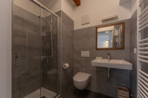 Zimmer „Materia“ in der Villa Patria mit Doppelbett, Holzmöbeln und Blick auf den Luganer See