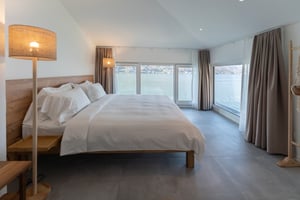 Zimmer „Riflesso“ in der Villa Patria mit Doppelbett, Holzmöbeln und Blick auf den Luganer See