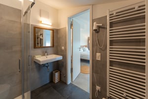 Zimmer „Riflesso“ in der Villa Patria mit Doppelbett, Holzmöbeln und Blick auf den Luganer See