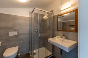 Zimmer „Riflesso“ in der Villa Patria mit Doppelbett, Holzmöbeln und Blick auf den Luganer See