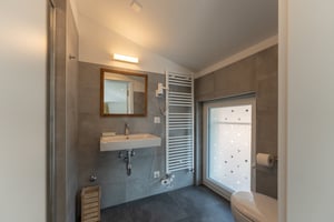 Das Zimmer „Scirocco“ in der Villa Patria mit Doppelbett, Holzmöbeln und Blick auf den Luganer See