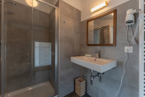 Das Zimmer „Scirocco“ in der Villa Patria mit Doppelbett, Holzmöbeln und Blick auf den Luganer See
