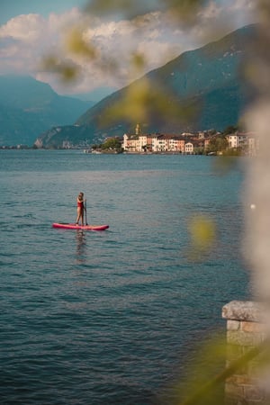 Ragazza in costume rosso attraversa il lago sul suo stand-up-paddle